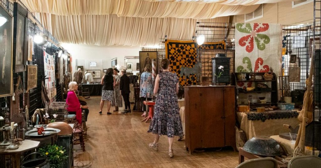People walk through aisles of high-end antiques.